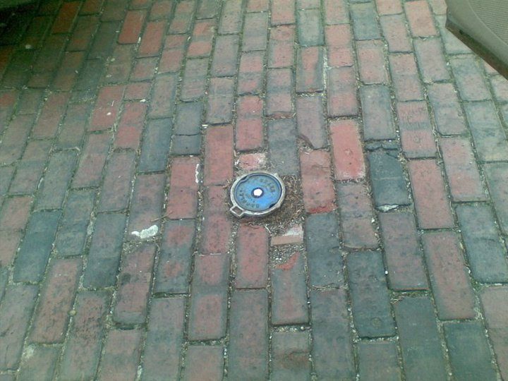 White packaged anode with red lead in a dug hole.