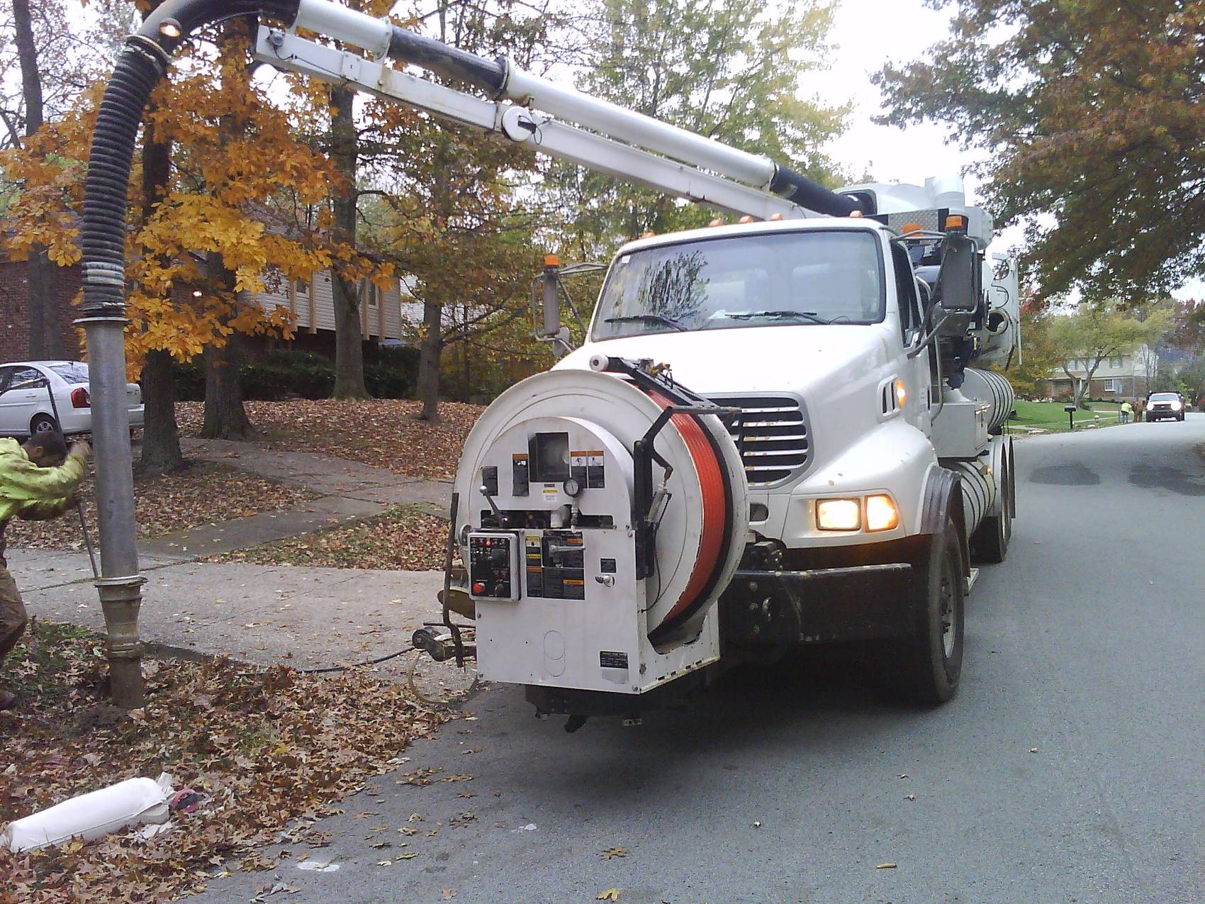Orange infrared asphalt heater with a propane tank on cracked pavement.