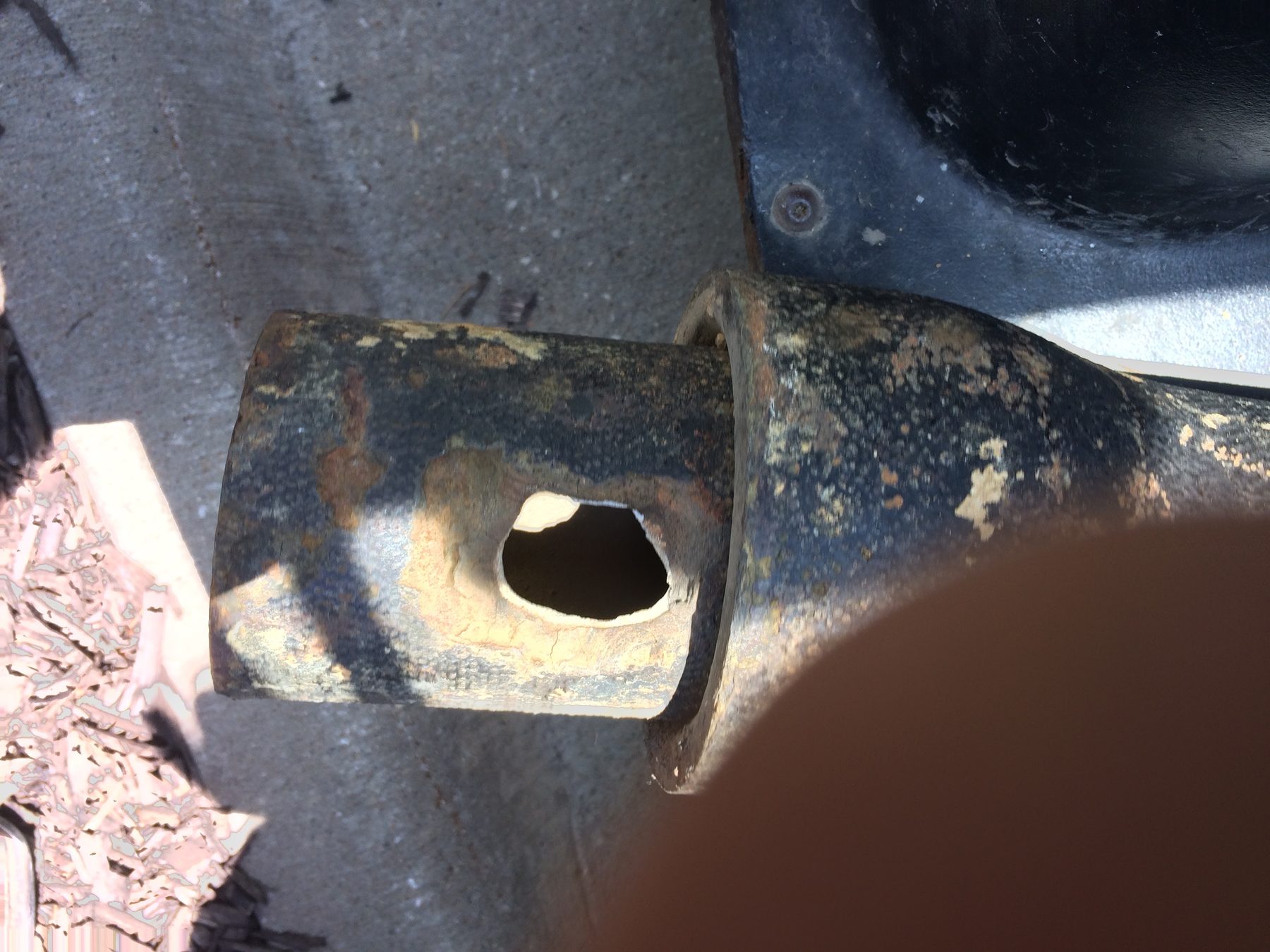 Rusted pipe with a hole eaten through the wall.