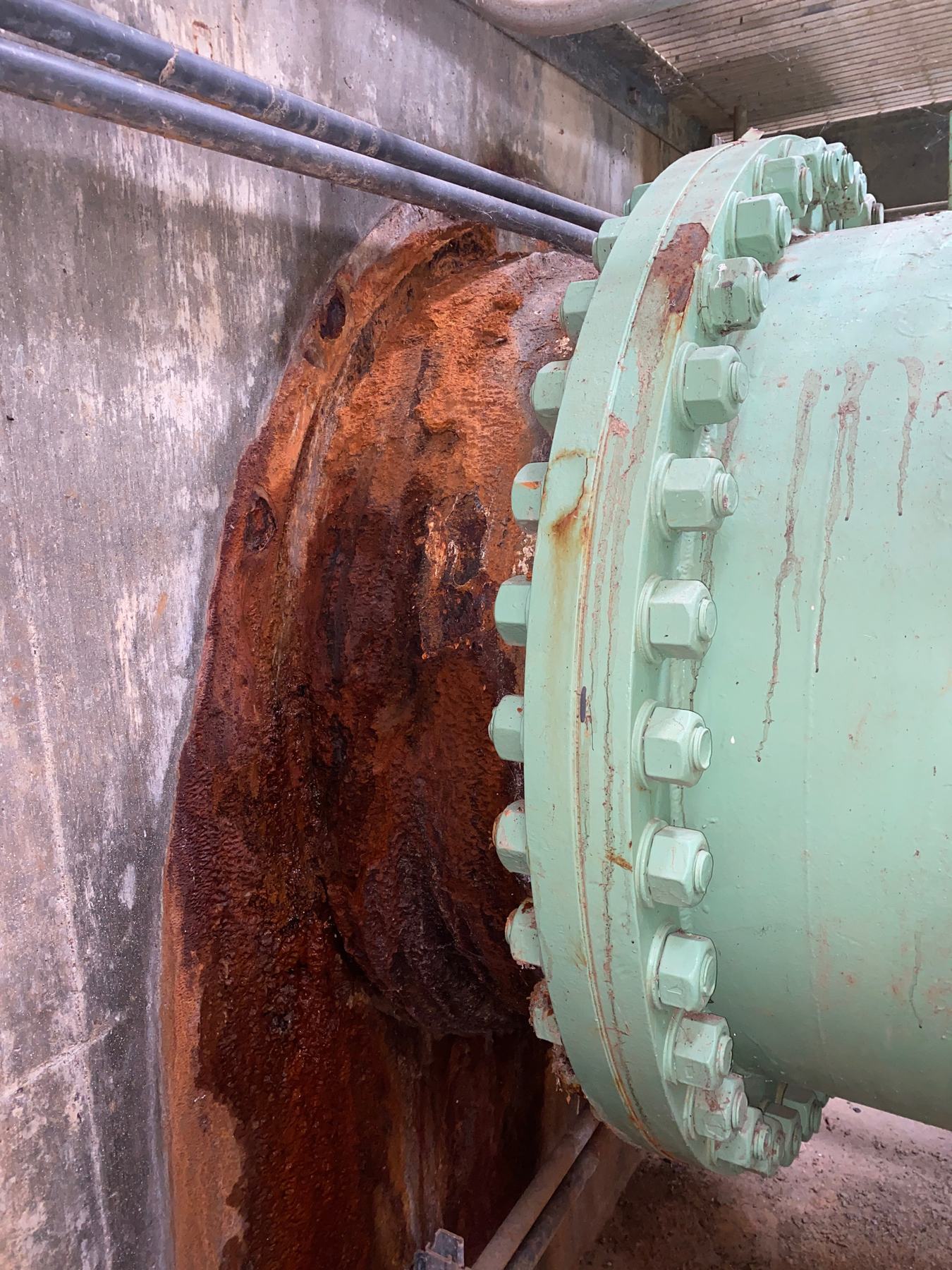 Heavily corroded pipe connection at a concrete wall