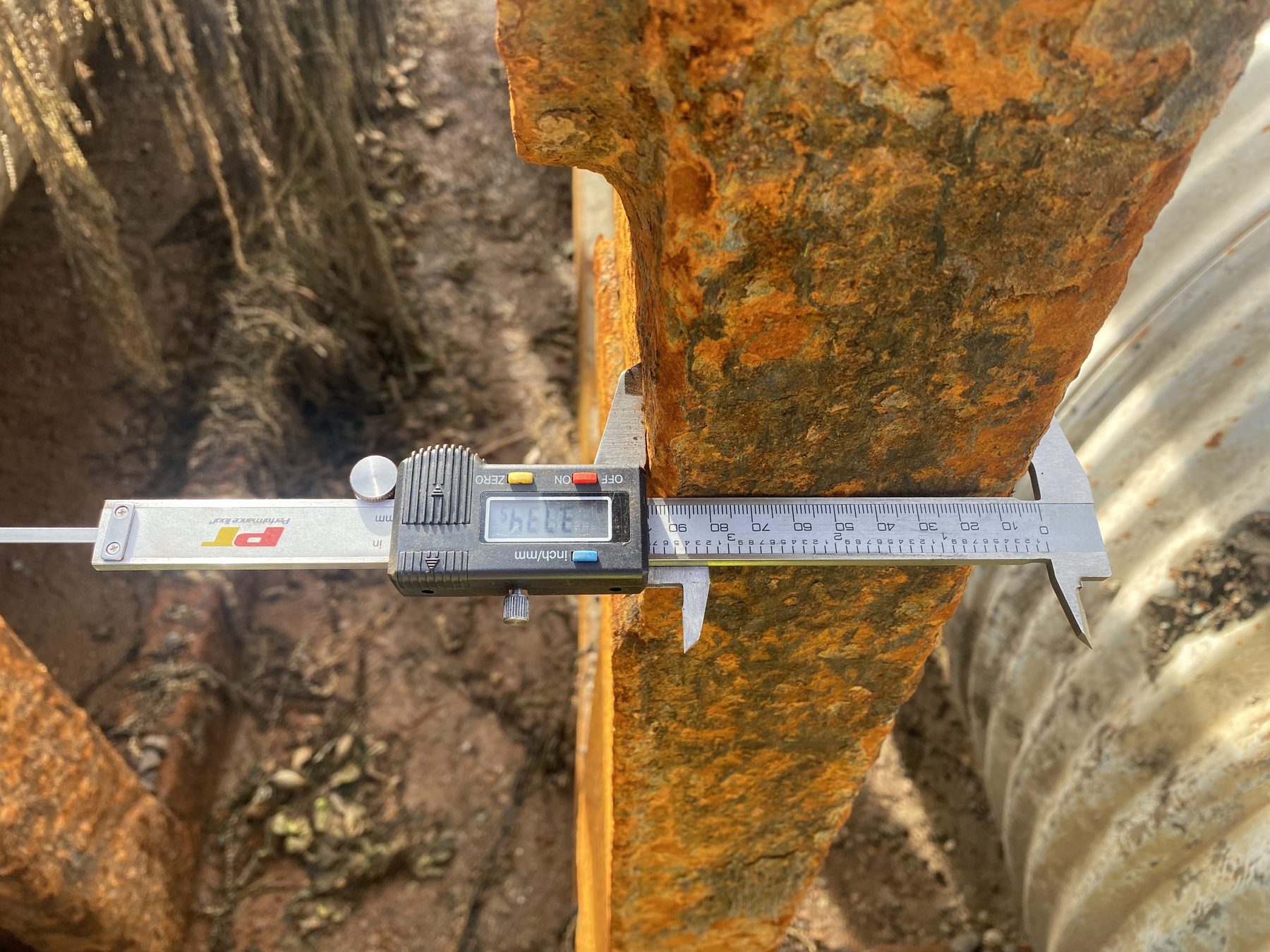 Digital caliper measuring remaining thickness of a rusted steel plate