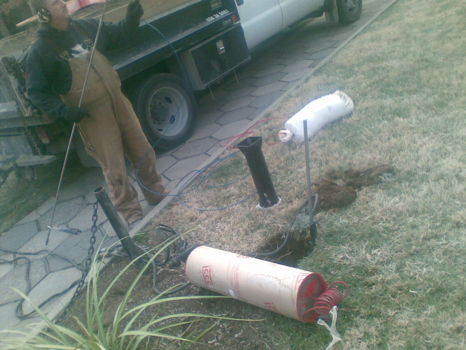 White vacuum truck with boom and hose at a curb.